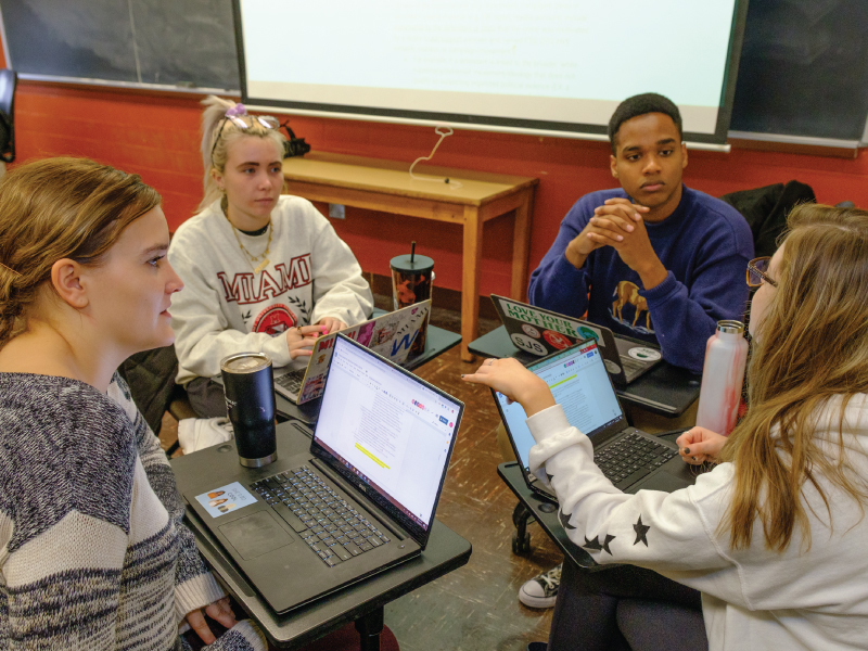 A group of 4 students discussing a topic in class.
