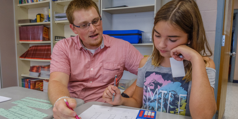 Education major working with a student during a hands-on learning exercise.