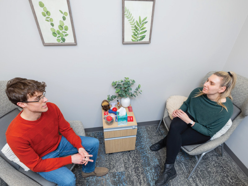 Psychology student conducts a one-on-one observation session in a counseling-style setting.
