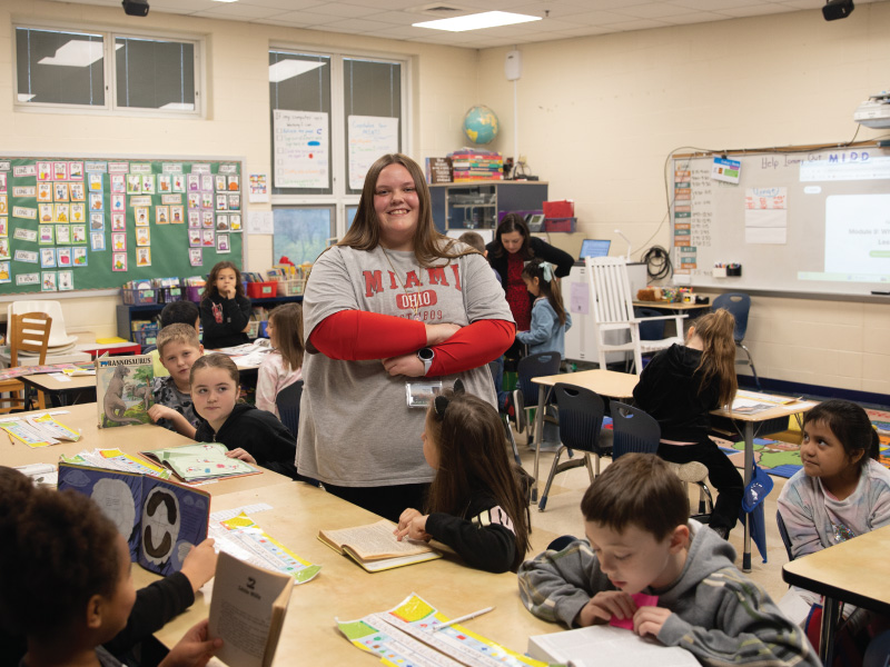 Hazel Moon smiling standing in the center of her classroom.