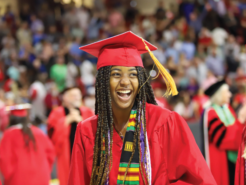 Student in her cap and gown smiling after receiving her diploma