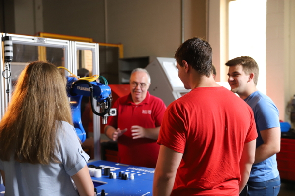 Students working with a robotics arm.