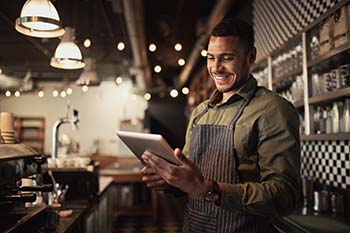A man working in a coffee shop and working with an iPad