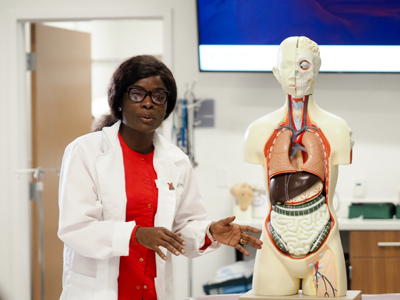 Effe Addae talking to a group of students next to a skelton.