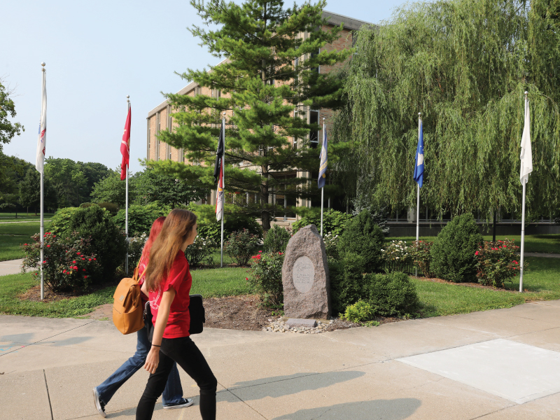 Students walking in front of the veterans memorial on the Hamilton campus.