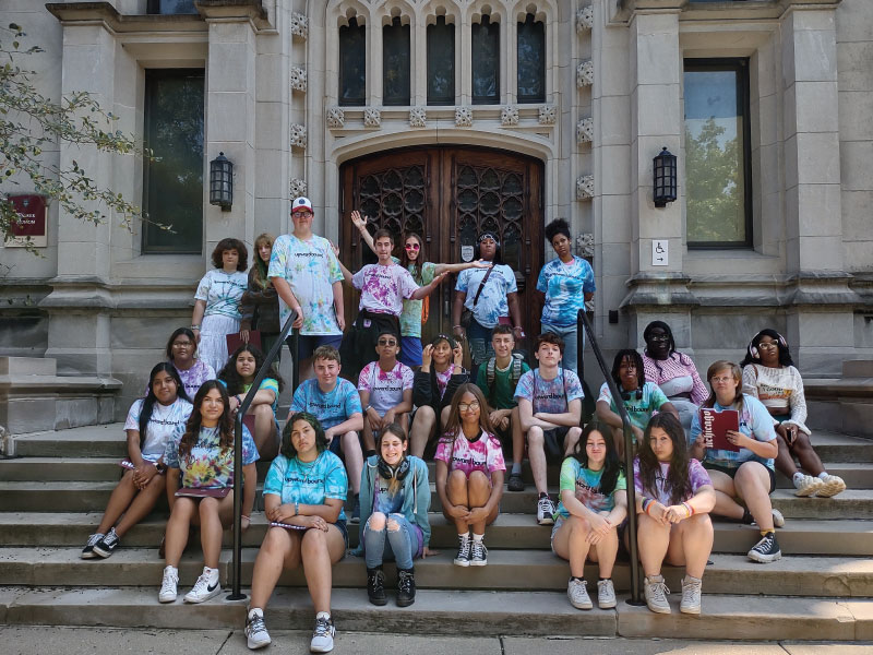 Group photo of all the students in Upward Bound standing on the steps in front of a church.