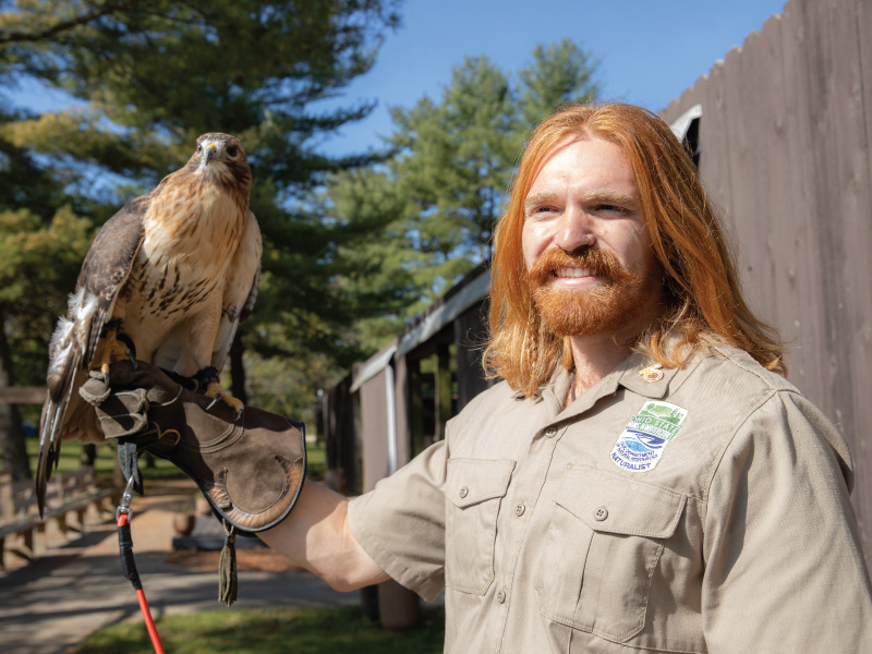 Skylar Gries holding Adena the red-tailed hawk on his arm.