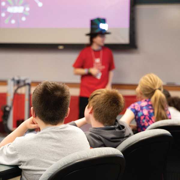 ENT student ambassador giving a presentation to a group of young students at a school.