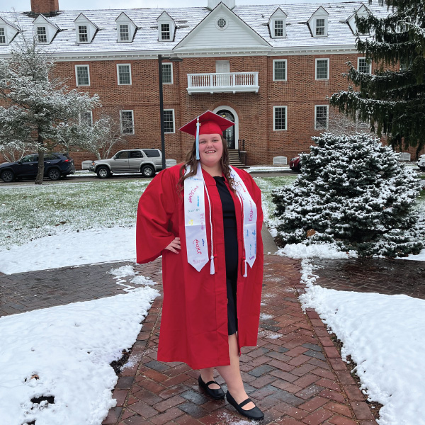 Hazel Moon in her cap and gown outside with snow on the ground.