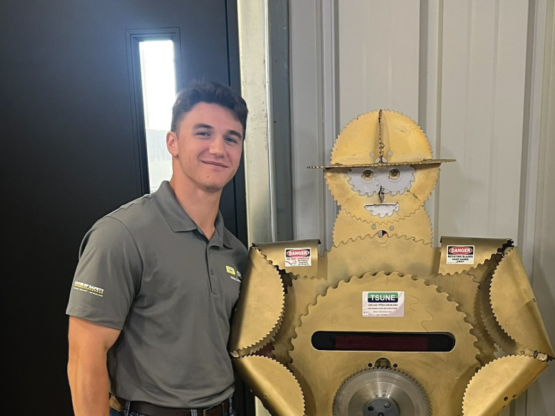 Stephen Malamisuro, Engineering Technology major standing next to a robot made of metal. 