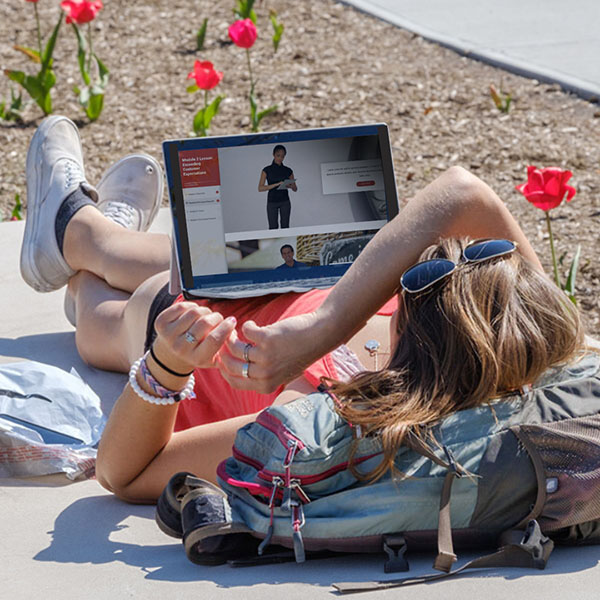 A student relaxing with her computer outside