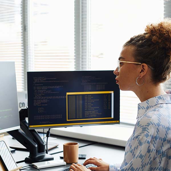 A woman programmer working with multiple monitors