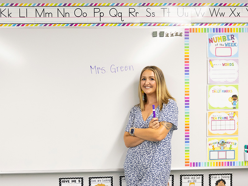 A preschool teacher standing in front of the white board