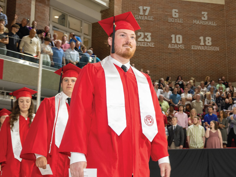 Student walking in his cap and gown during graduation.