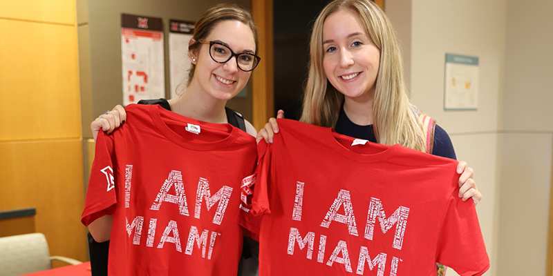 Students holding up red I am Miami tshirts