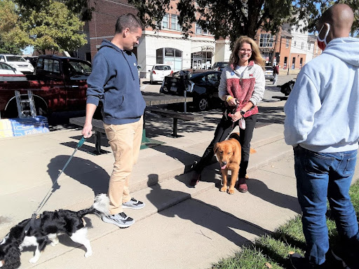 Renate Crawford with a golden retriever speaking to two others at the uptown park in Oxford.