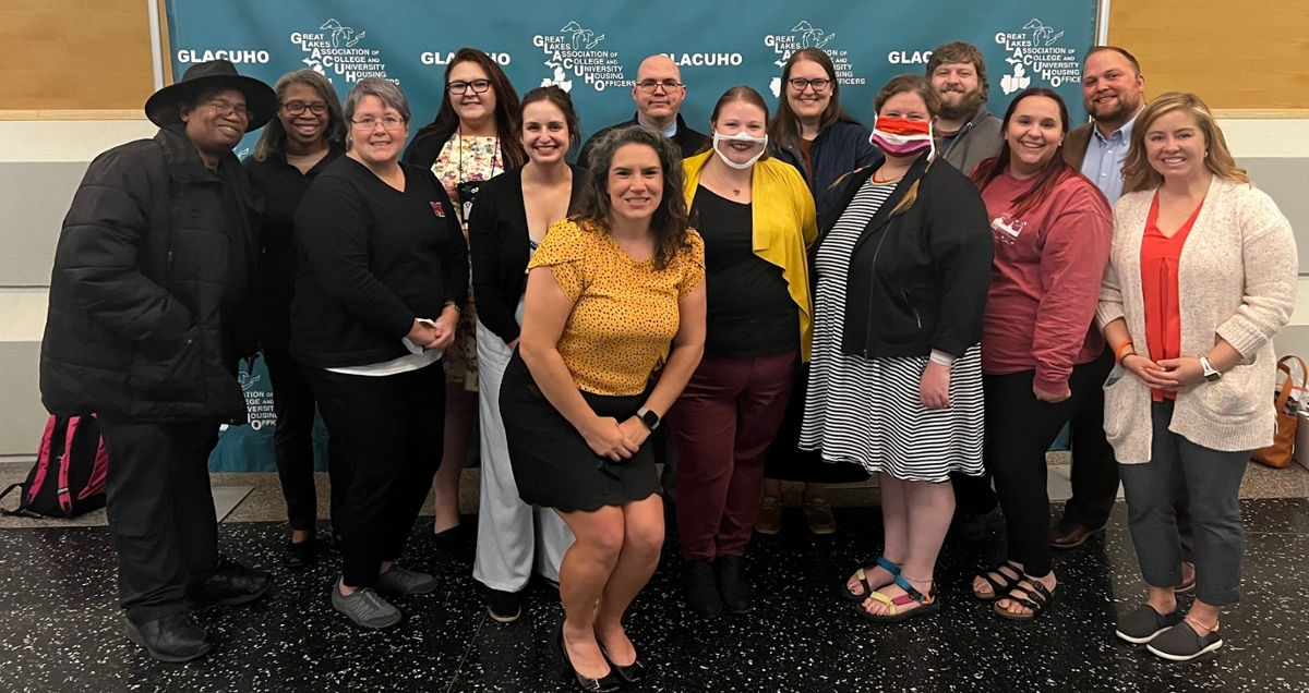 Group of about 20 staff members from the Office of Residence Life in front of a GLACUHO background.