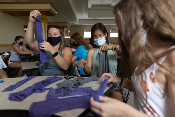 Students wearing masks and cutting up t-shirts to make dog toys during a welcome weekend service project.
