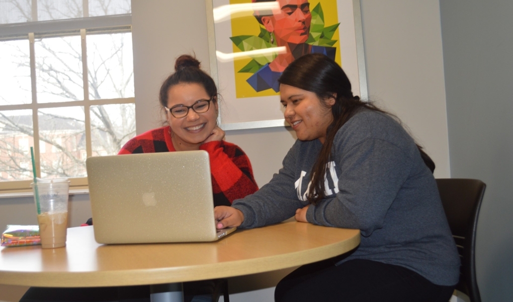 Two female students in the tutoring center, working together at a small table.