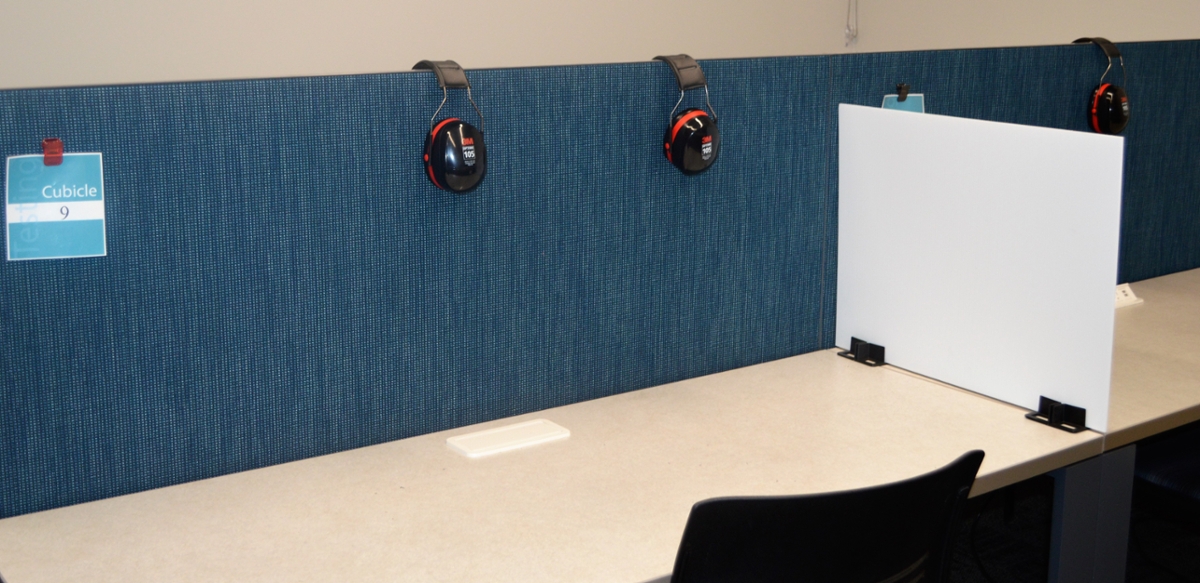 Cubicle desk with dividers, noise cancelling headphones. 
