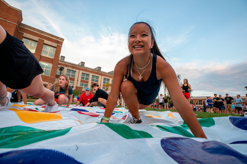 Group of students playing jumbo twister on a campus lawn