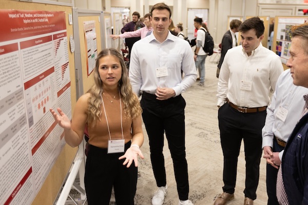 A student presents her research to visitors at the research forum