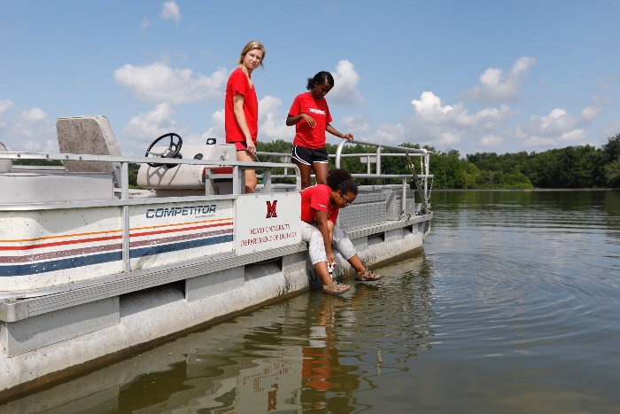 Students testing water samples from a boat in a lake