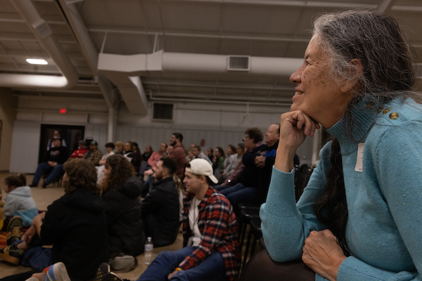 a woman resting her head on her hand while watching a group perform