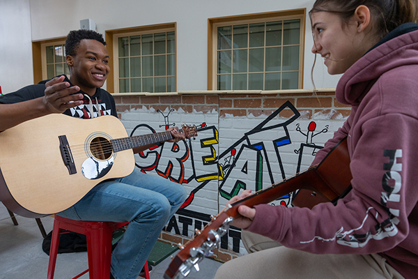 two students making music on guitars together