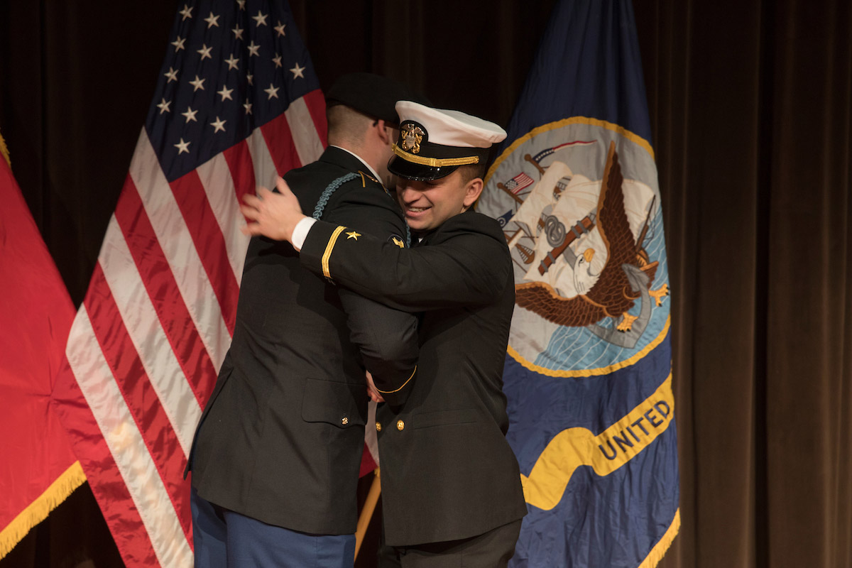 A ROTC student hugs an officer at a commissioning ceremony.