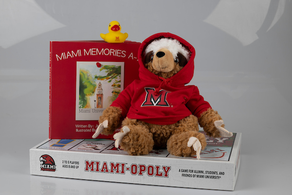 A stuffed sloth, book, and yellow rubber duck on top of a Miami-O-Poly Game