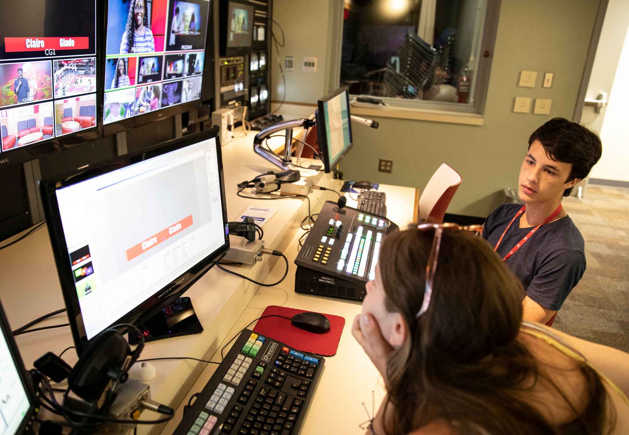 Two Students sit in front of monitors in the control room in Williams Hall