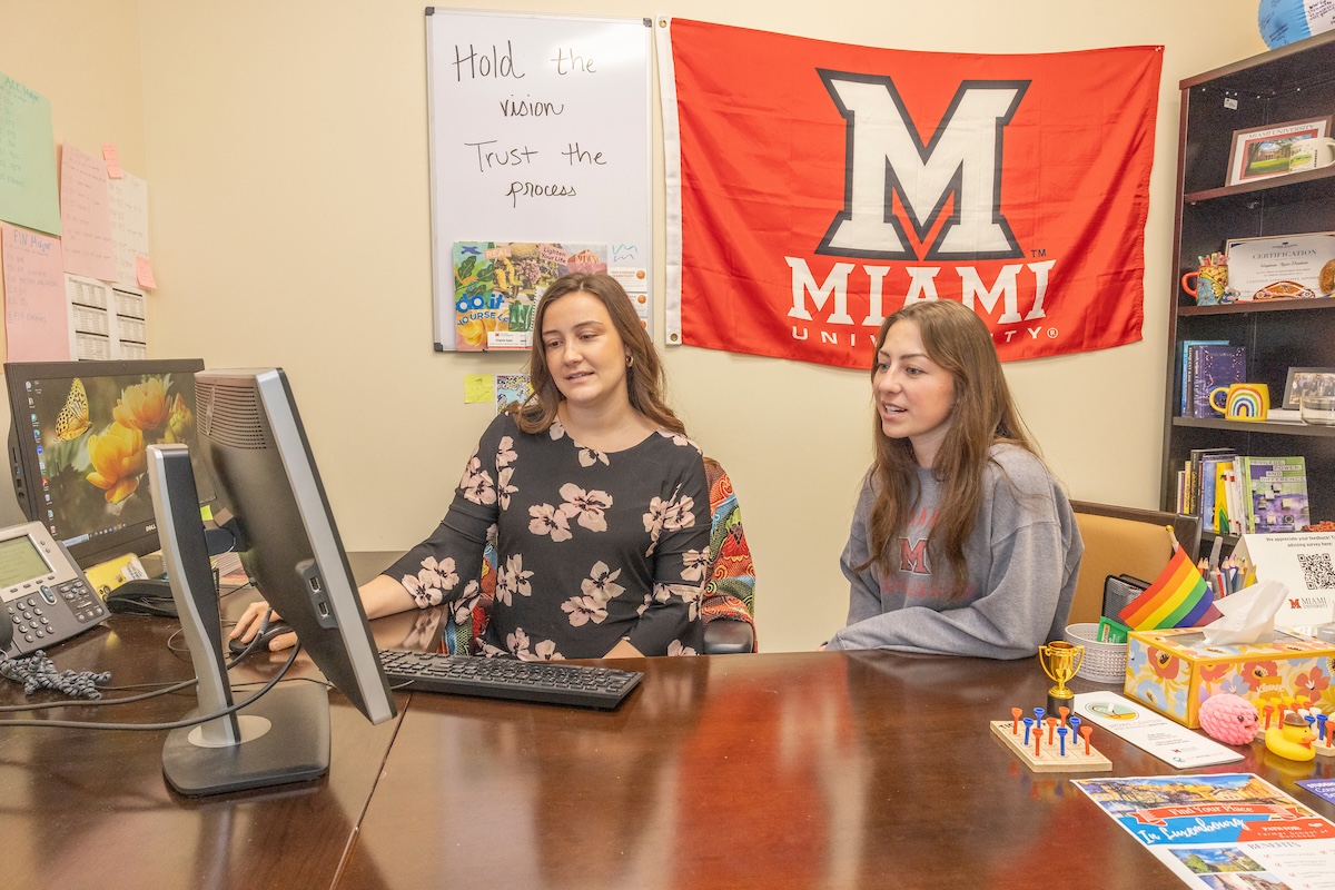 An academic advisor meeting with a student at her desk