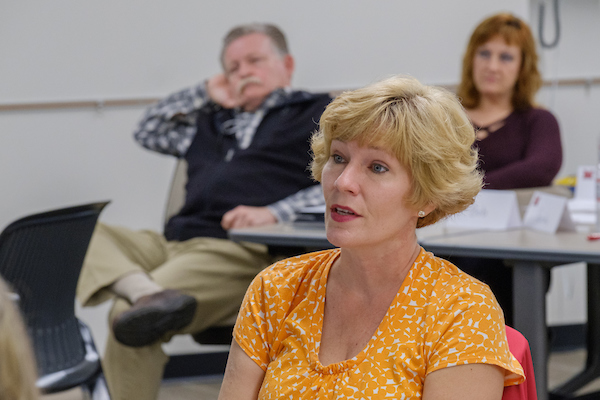 Three workshop attendees sitting in a conference room listening to a presenter