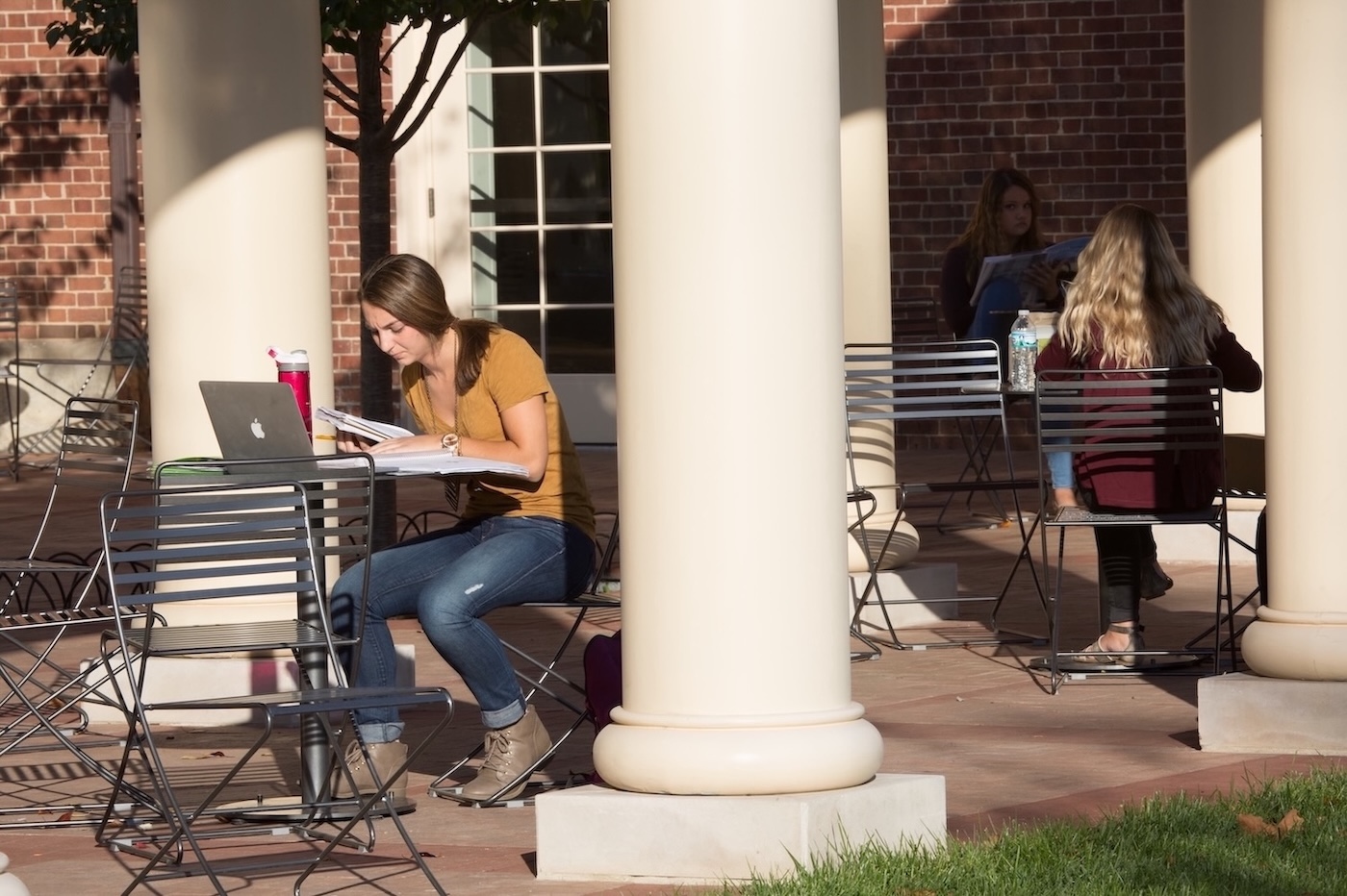 Two students working on homework at tables on the patio of the Armstrong Student Center.