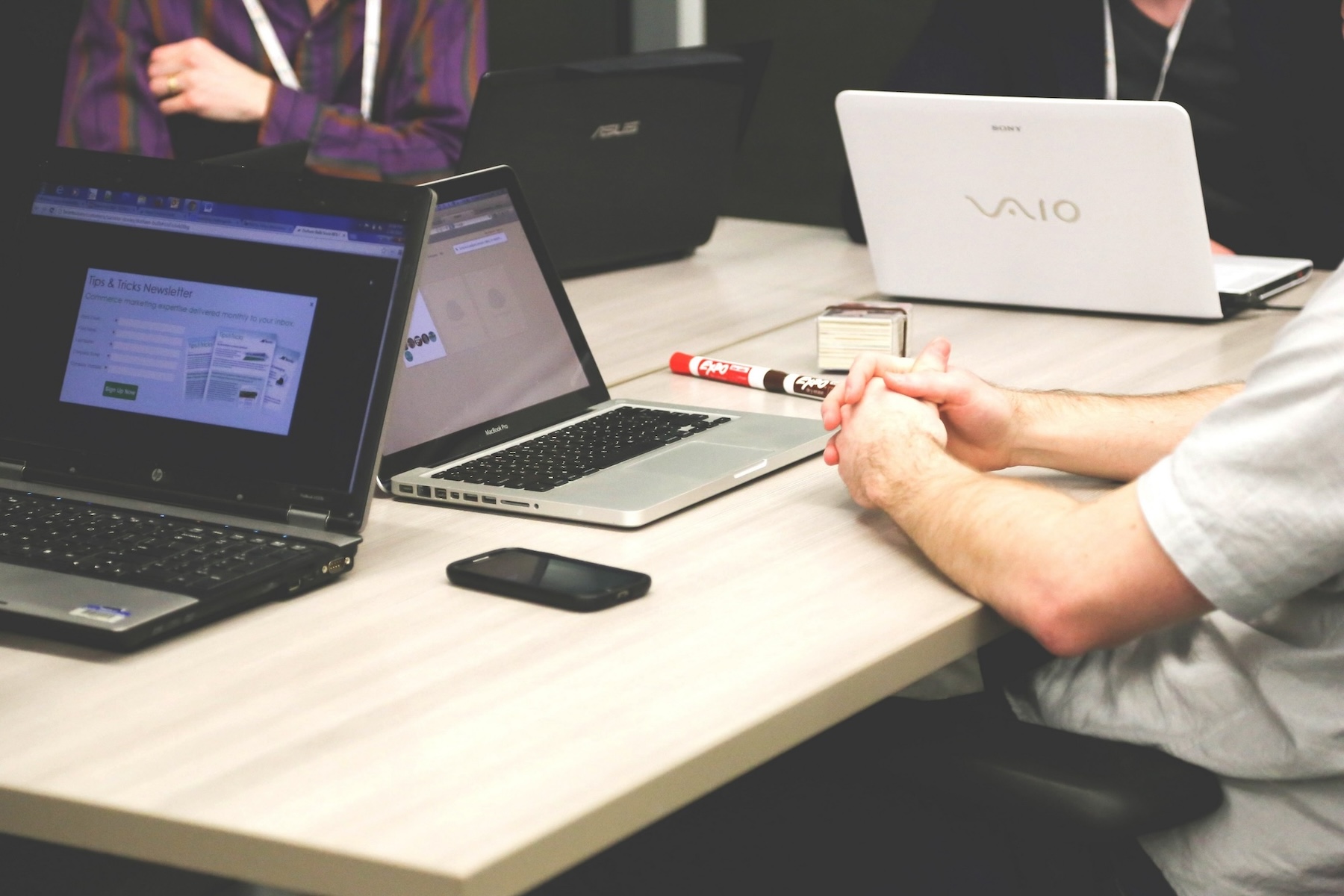 Several people sitting around a desk each with a laptop in front of them