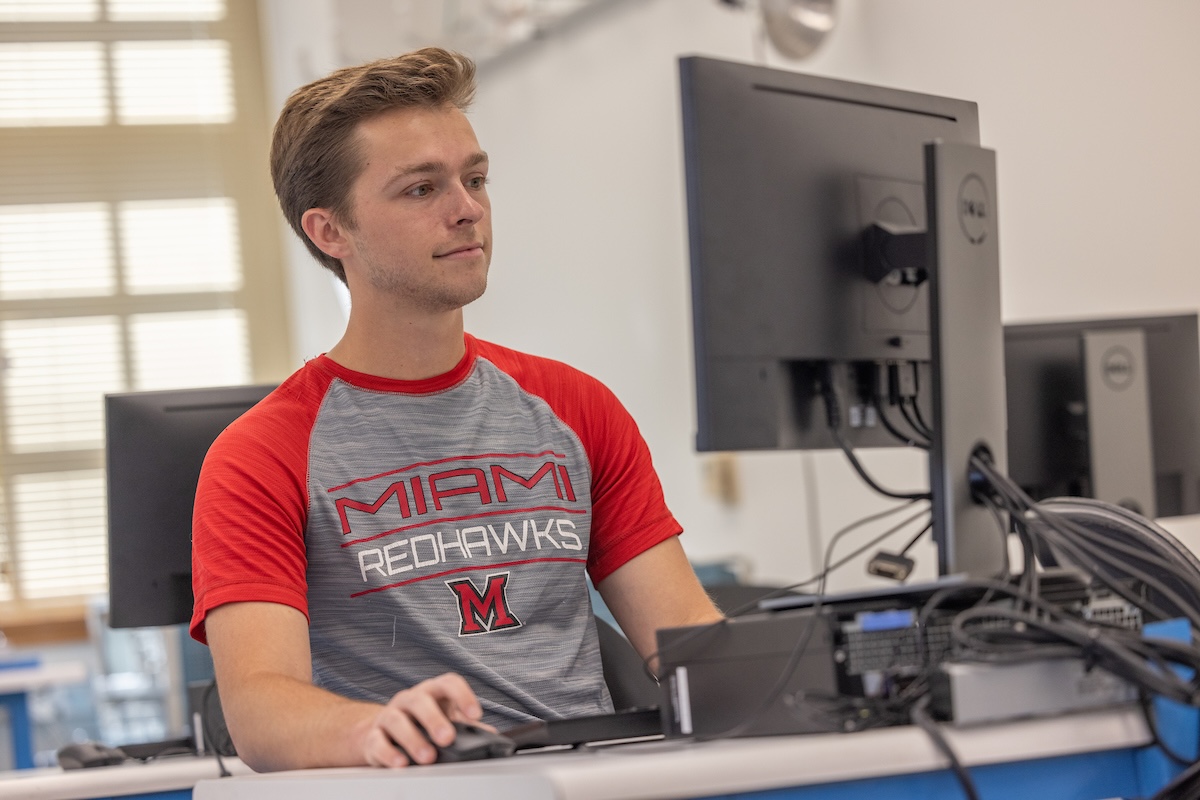 A student looking at a computer monitor while working in a computer lab.
