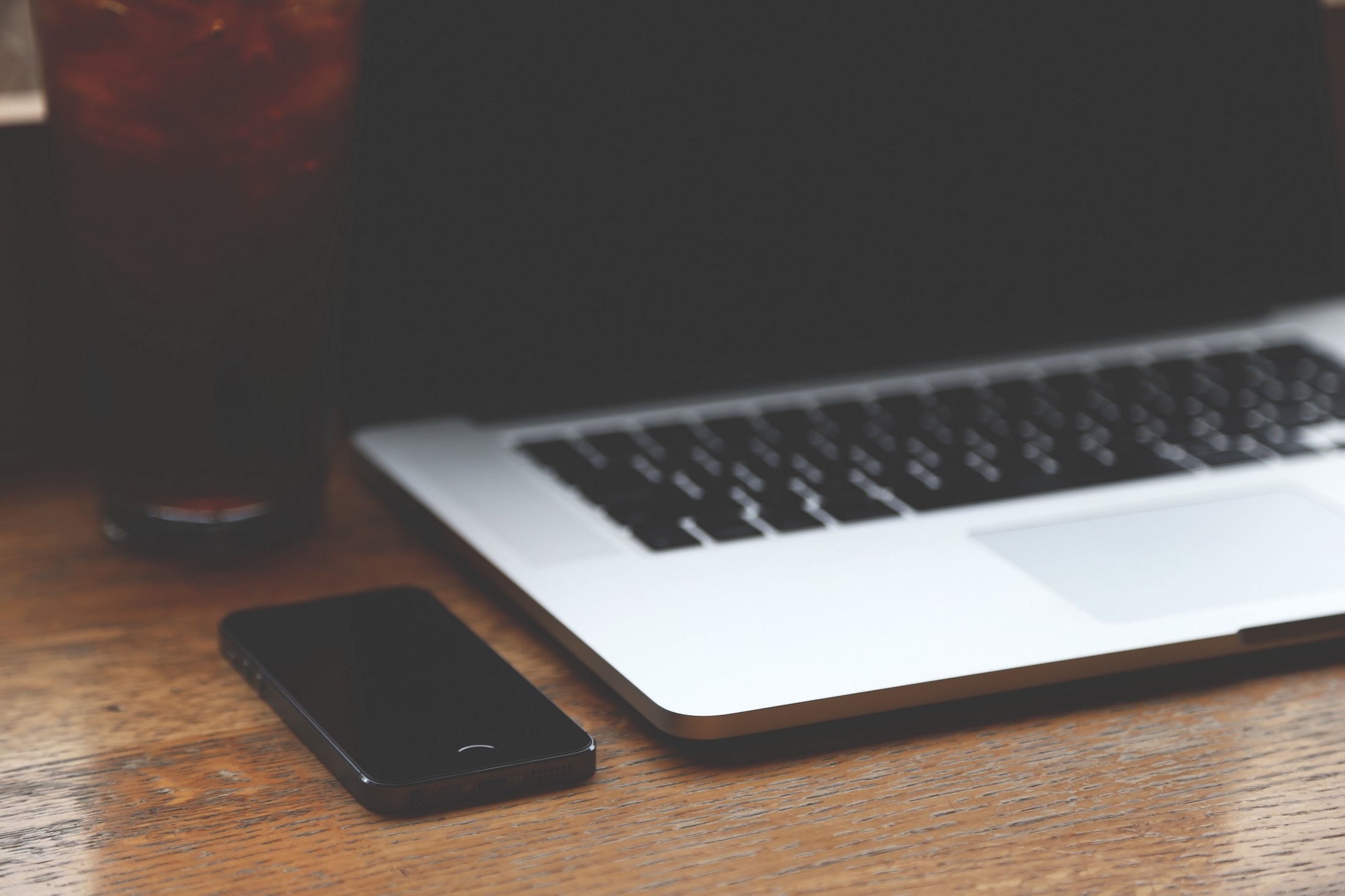 A phone sitting on a desk next to a laptop computer.